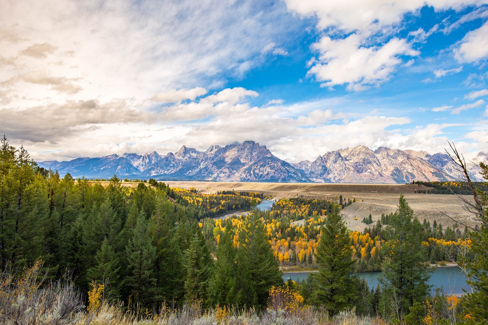 The Snake River winding through the autumn valley below the full Teton range